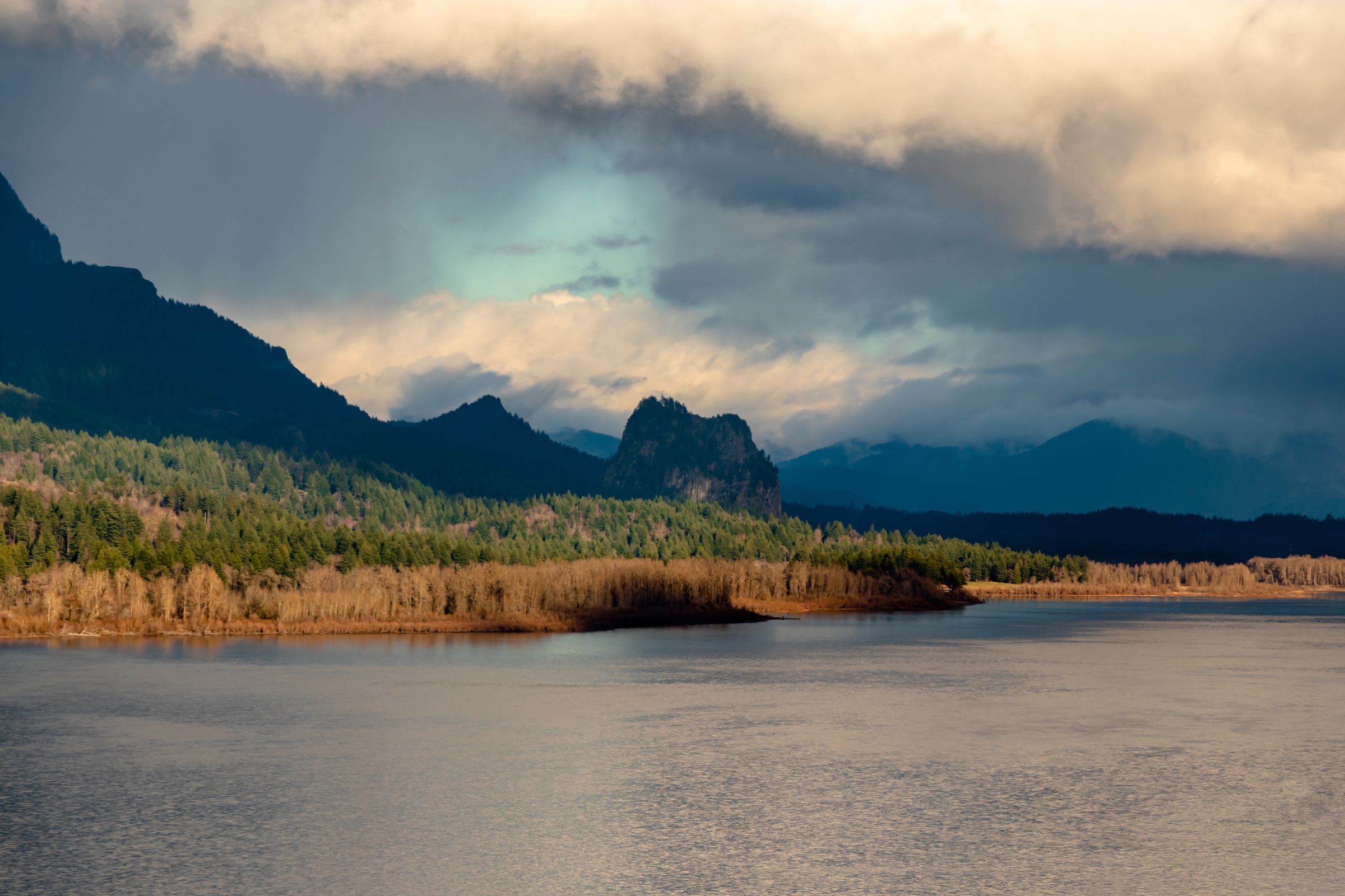 River canyon with storm light over forested mountains